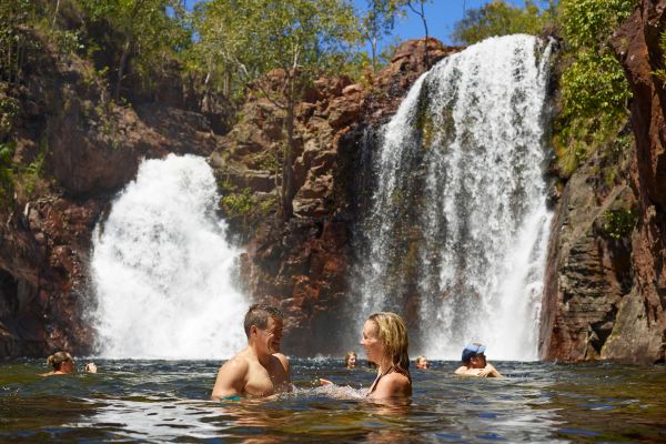 A man and woman swimming at a waterfall