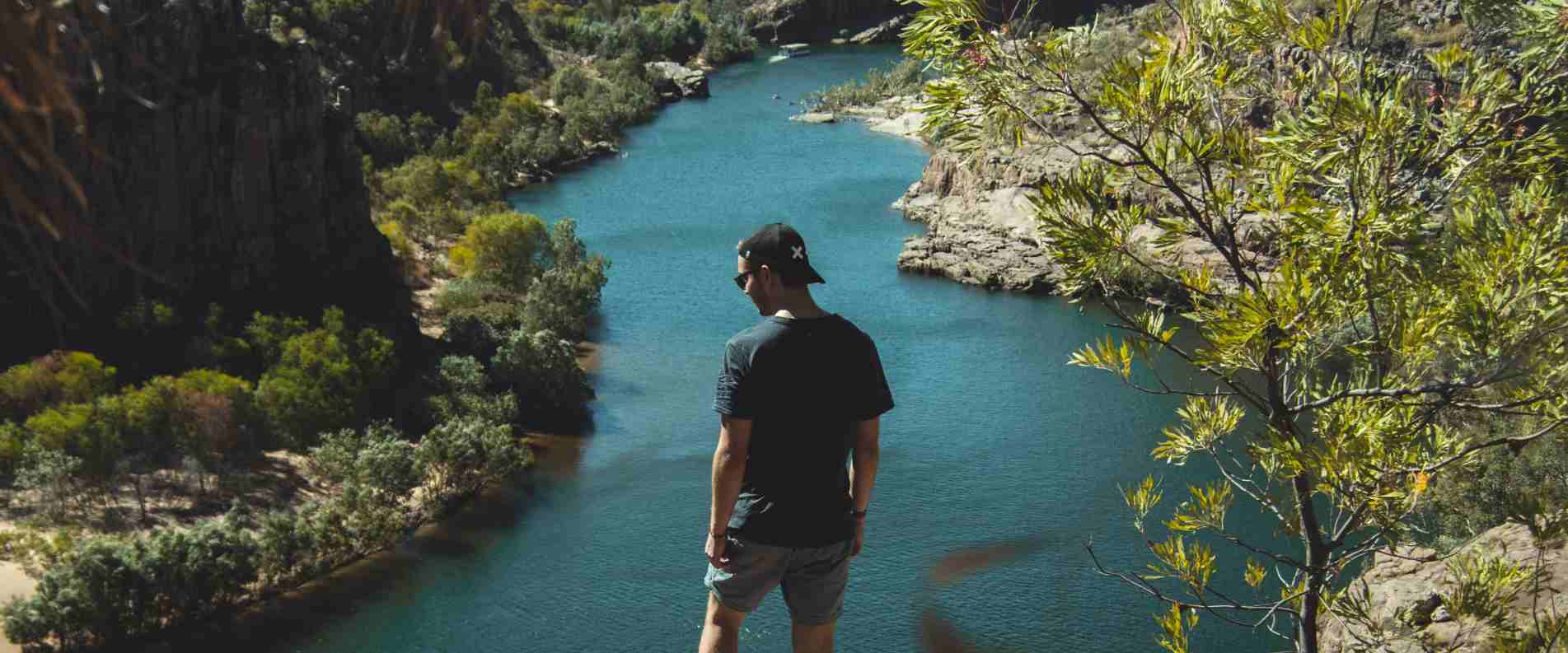man standing on cliff overlooking Katherine Gorge which is filled with water