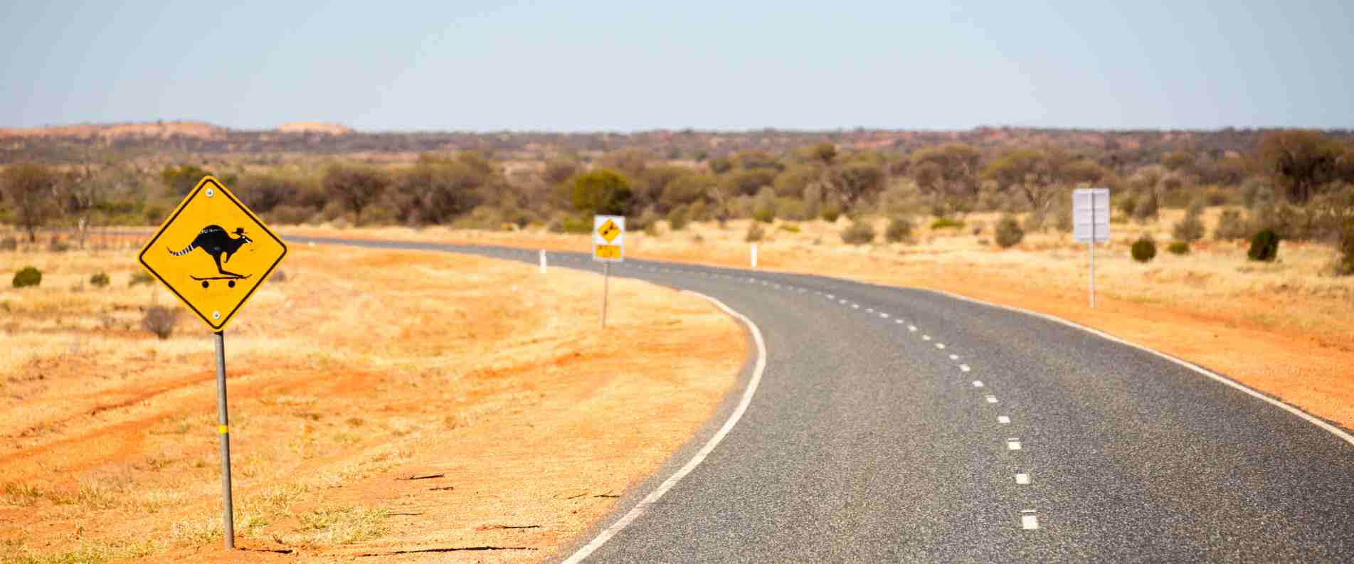 outback road in northern territory with kangaroo warning street sign