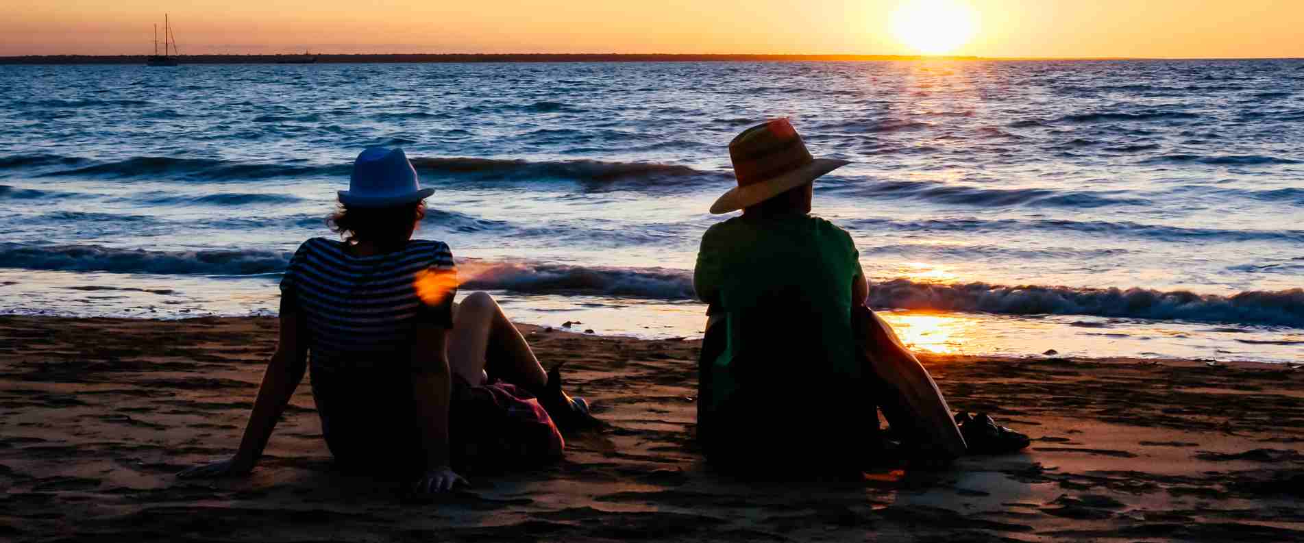 two people sitting on beach in Darwin at sunset